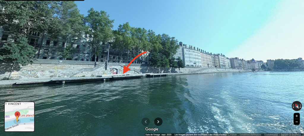 Vue sur les berges du Rhone a Lyon avec immeubles haussmanniens, arbres et eau bleue en premier plan
