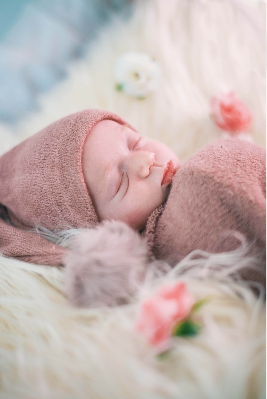 Photo d'un nouveau-né endormi, entouré de fleurs délicates, capturé dans un style doux et naturel.