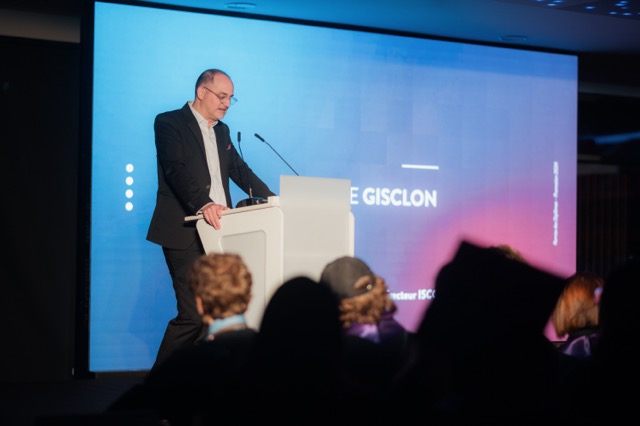 Prise de parole au pupitre devant l'écran géant pendant la remise de diplômes