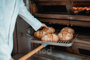 Pain artisanal fraîchement cuit au feu de bois dans le four traditionnel de la Maison Terrasson, une boulangerie artisanale reconnue pour ses méthodes ancestrales.