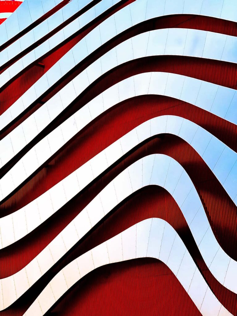 Façade architecture contemporaine avec motif ondulé rouge et blanc photographiée en style minimaliste Jack Fleming
