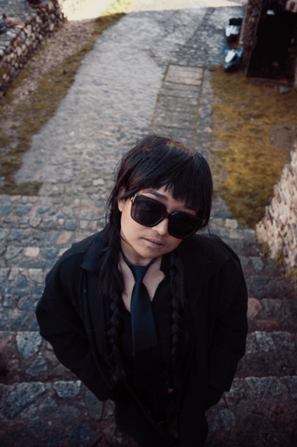 Portrait plongée d'une femme en lunettes noires sur escalier en pierre