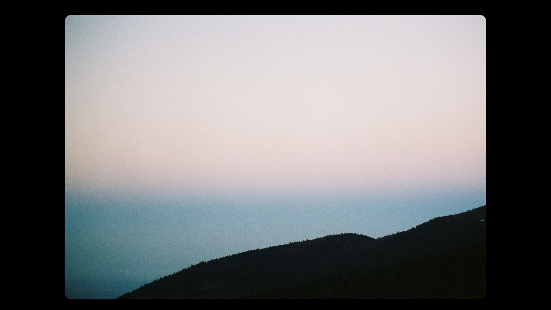 Paysage de montagnes en silhouette au crépuscule, ciel dégradé bleu pastel