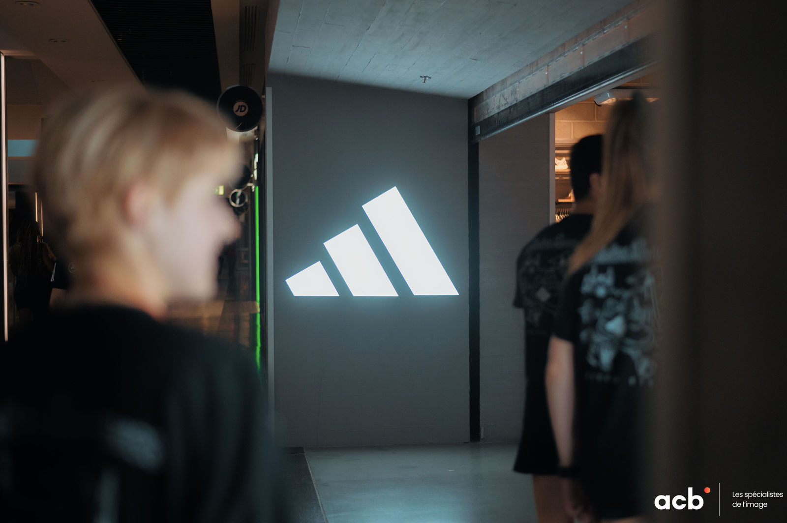 Deux participants observent un logo lumineux dans une salle d'atelier photo, cadre de formation professionnel