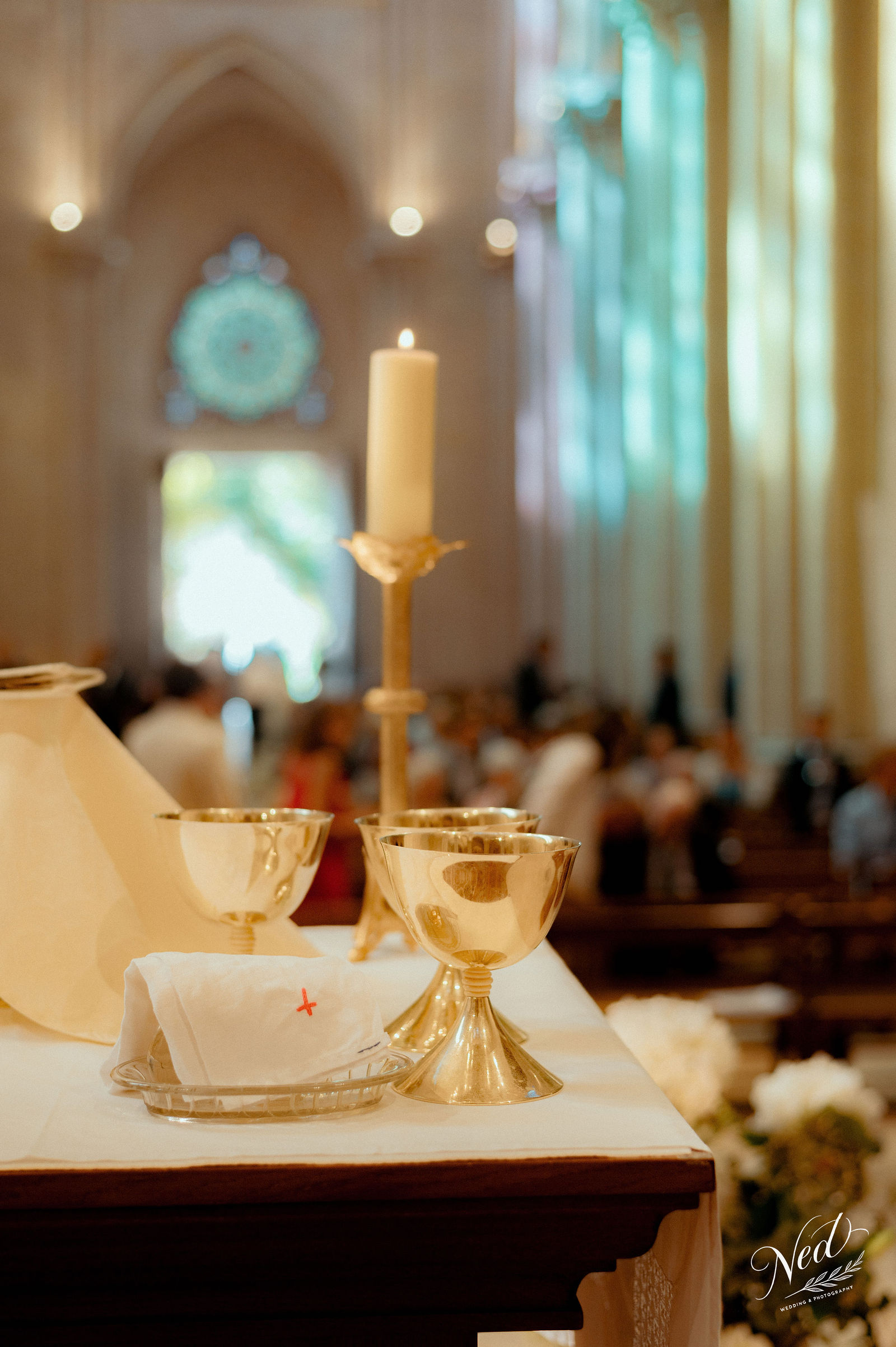 Calices dorés et cierge sur l'autel d'une église, assemblée floue en arrière-plan