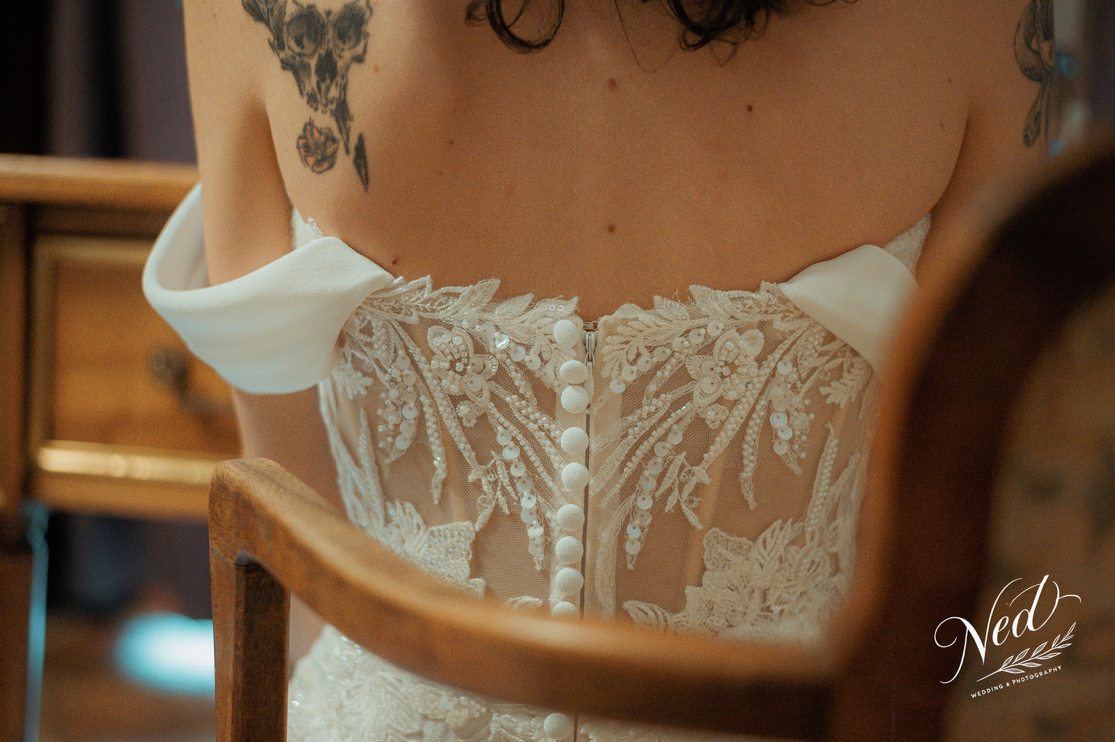 Femme en robe de mariée blanche avec dentelle et boutons perlés, vue rapprochée du dos et des détails