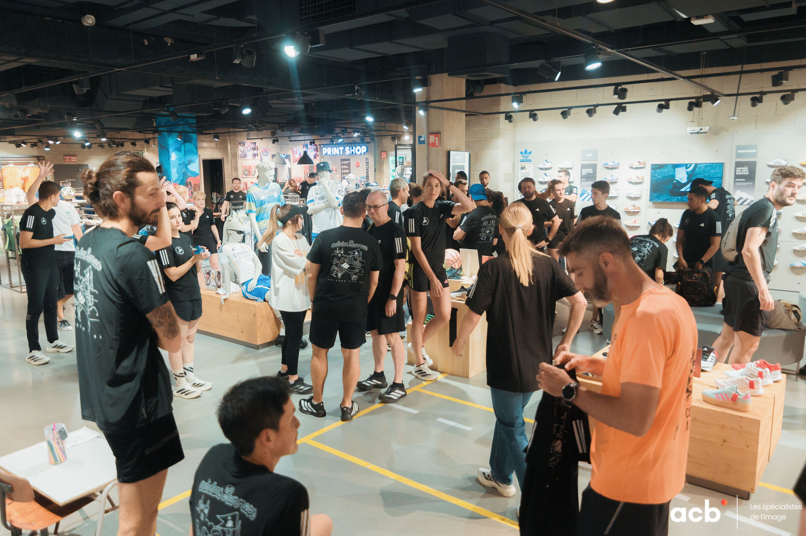 Groupe de participants réunis dans un magasin adidas, se promenant entre les stands et regardant les produits affichés aux murs