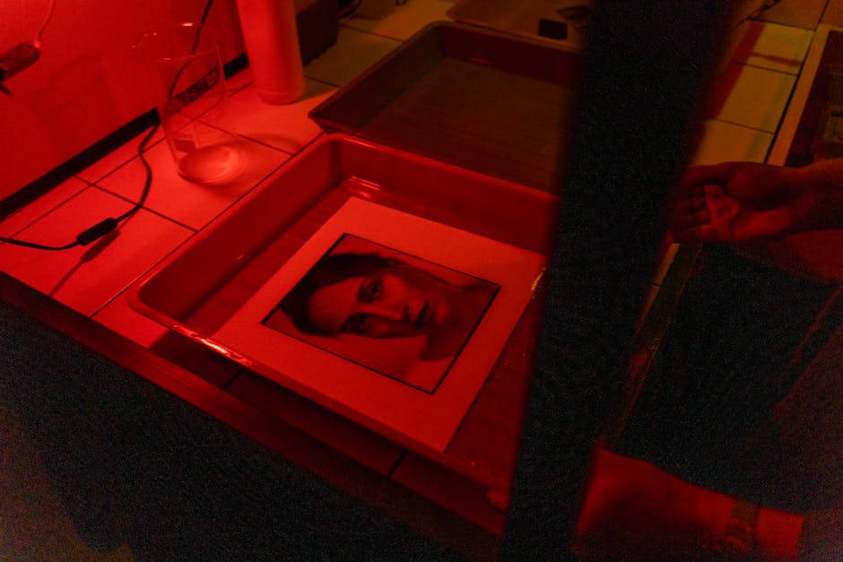 A portrait photograph is being developed in a darkroom under red lighting.