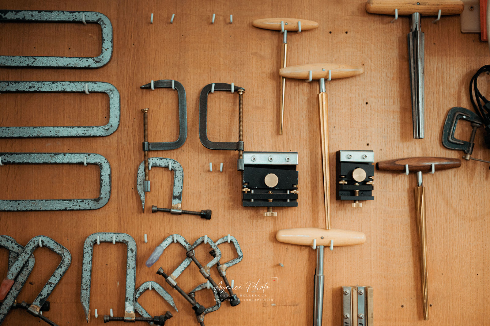 Serre-joints en fonte patinée, étaux et outils de serrage disposés sur panneau de bois avec trous de fixation