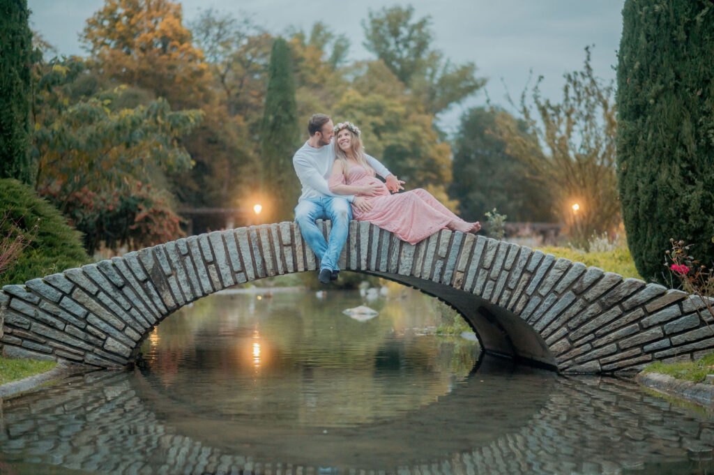 Homme et femme enceinte assis sur un pont en bois au-dessus d'un plan d'eau, entourés de végétation d'automne