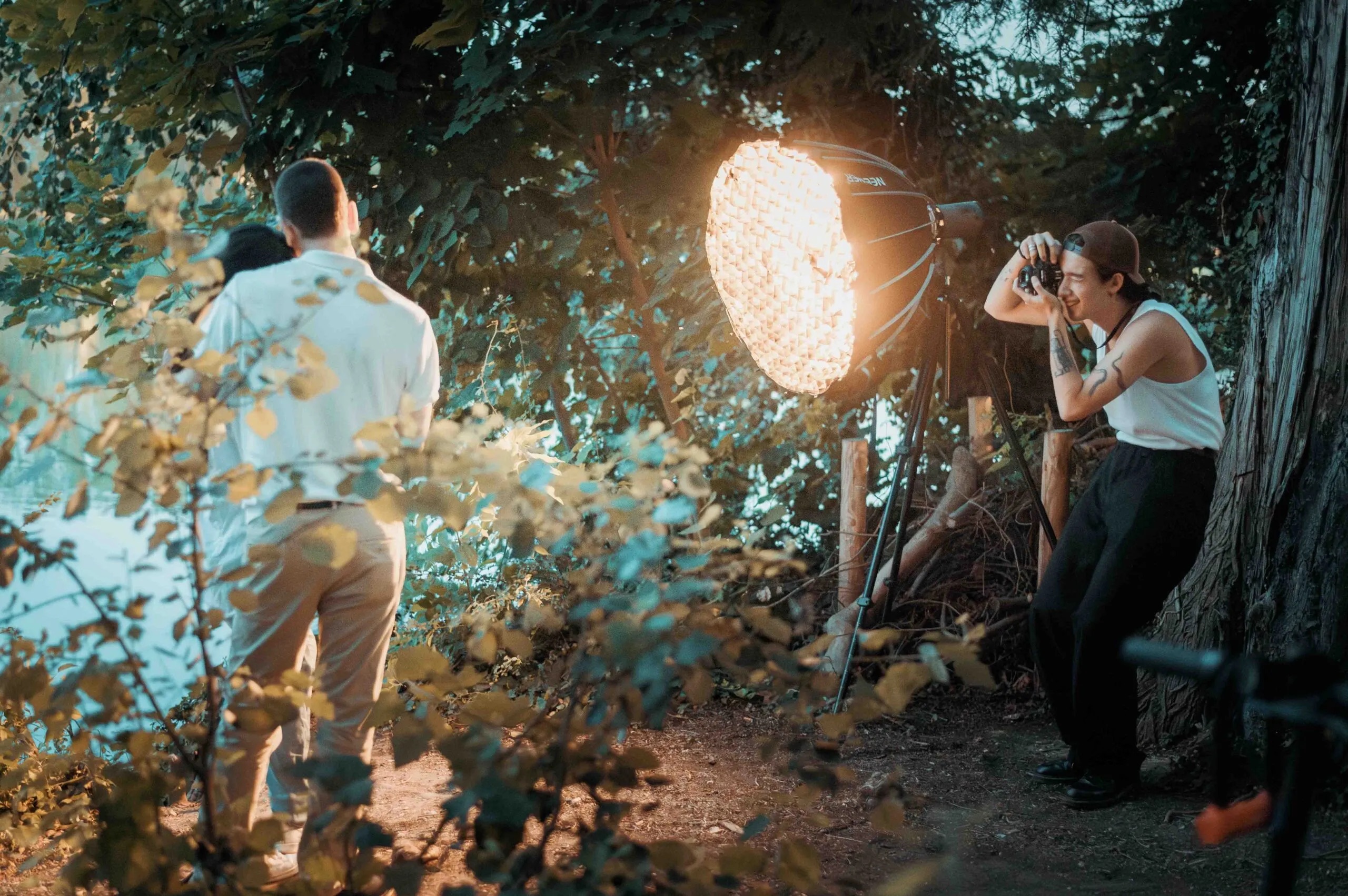 Formateur et participant posent sous un arbre avec projecteur de lumiere studio, stage photo pratique en nature