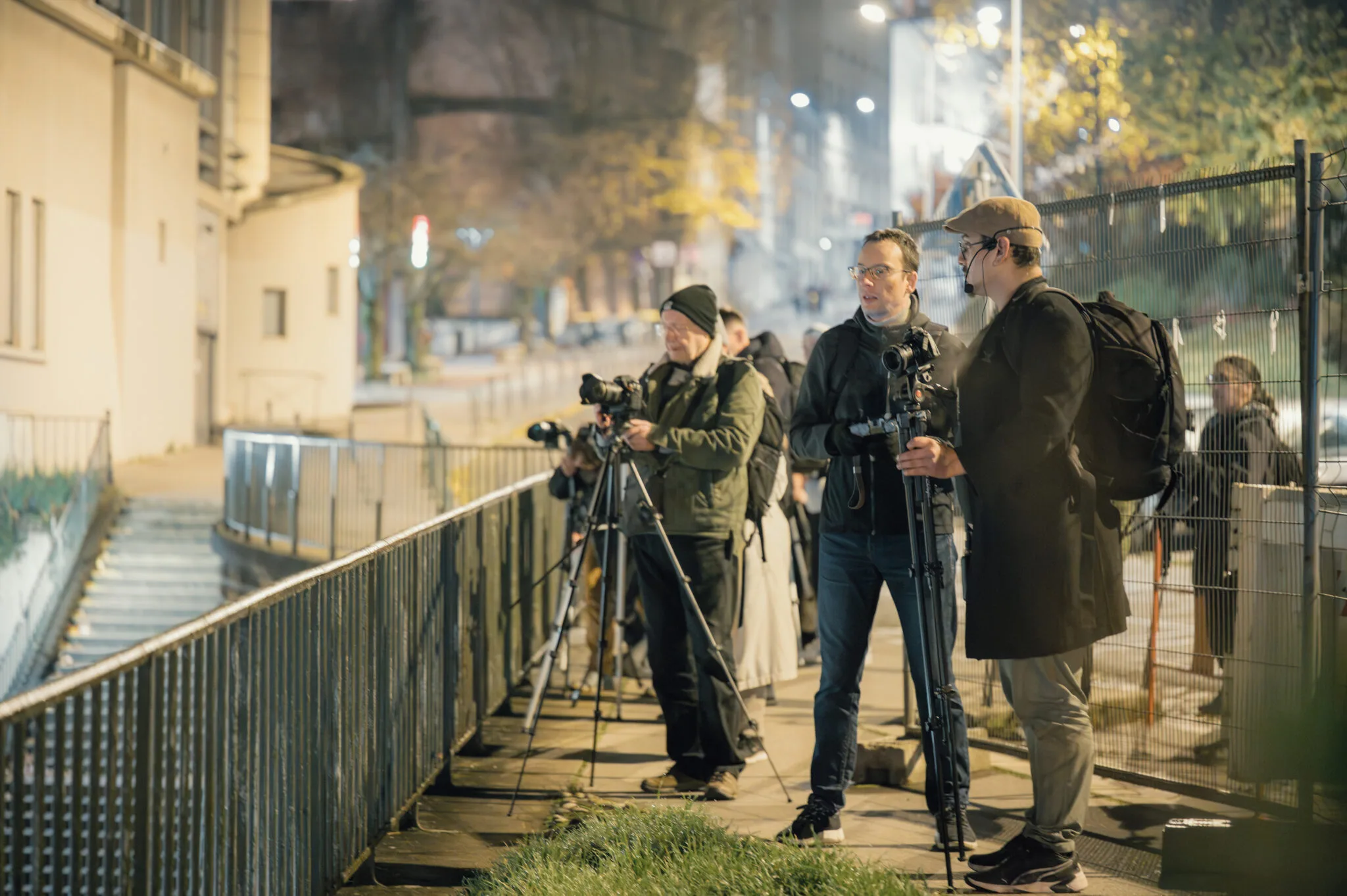 Stage photo nocturne &agrave; Lyon &mdash; quatre participants discutent r&eacute;glages sur une passerelle urbaine de nuit