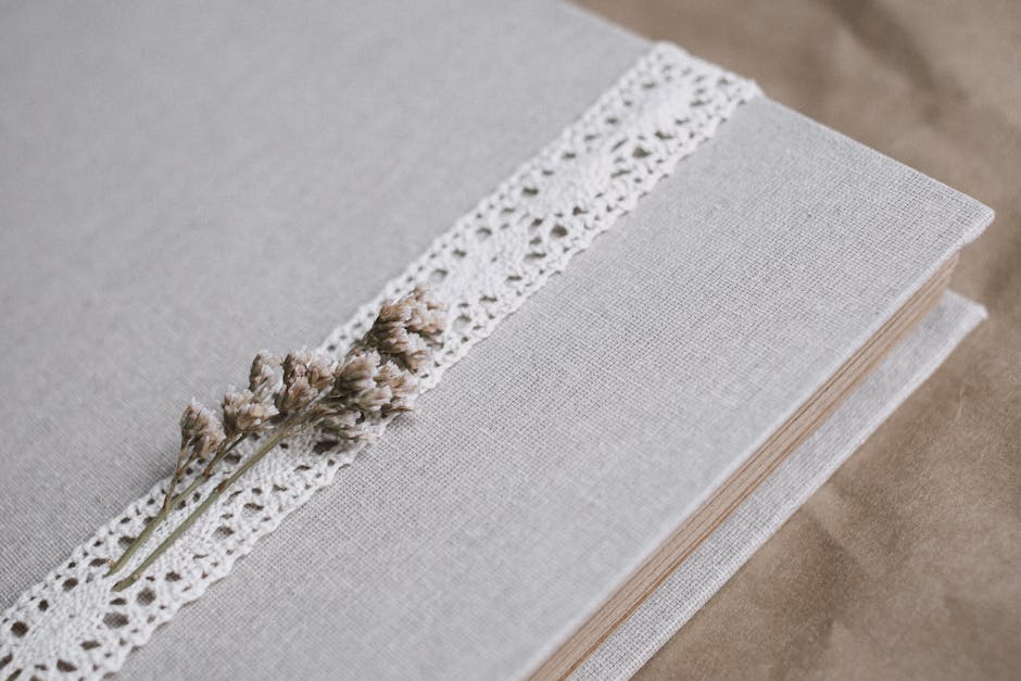 Linen-covered book with lace and dried flower detail, perfect for weddings or special occasions.
