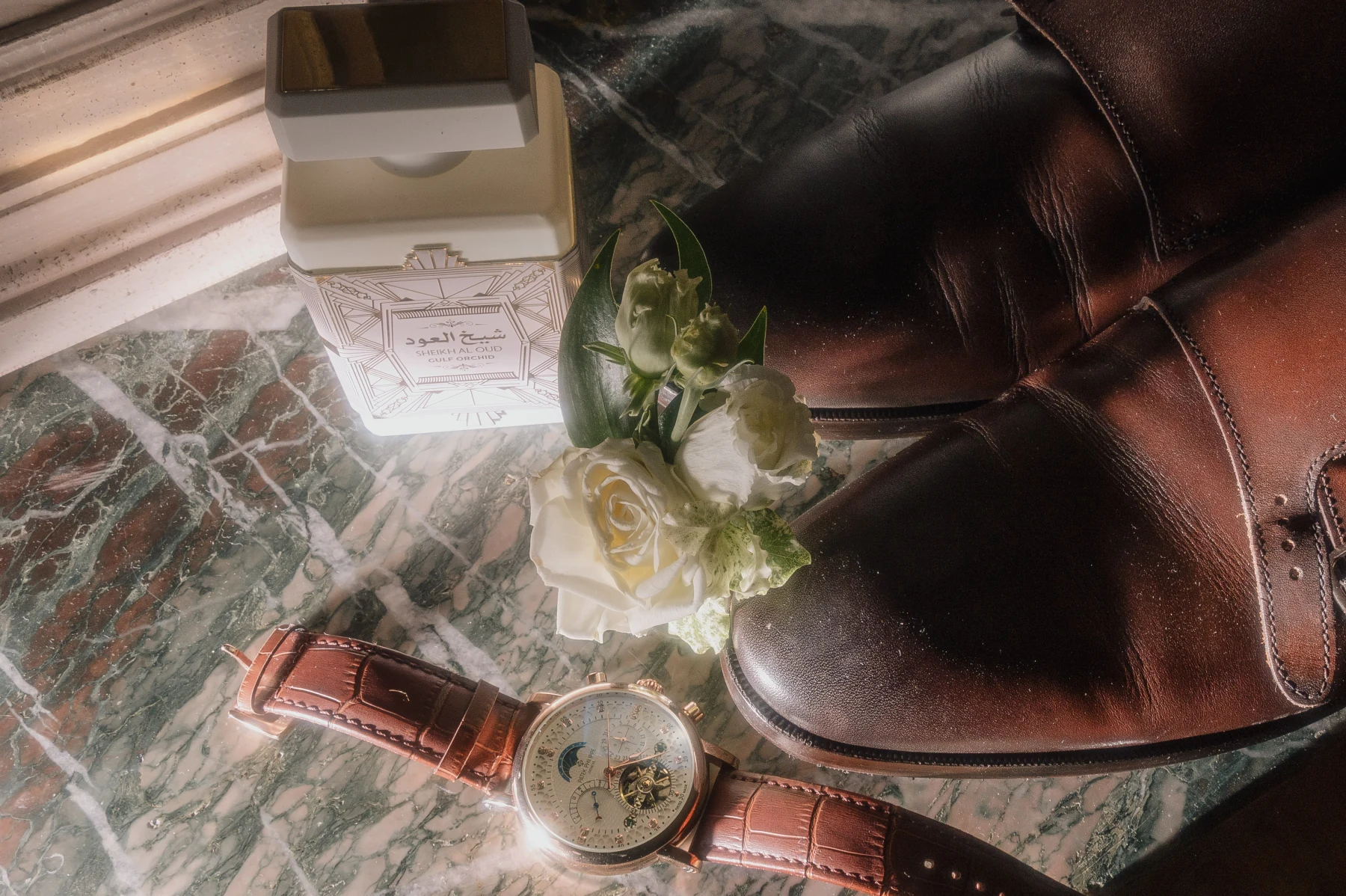 Mise à plat des accessoires du marié : montre, boutonnière, parfum et chaussures