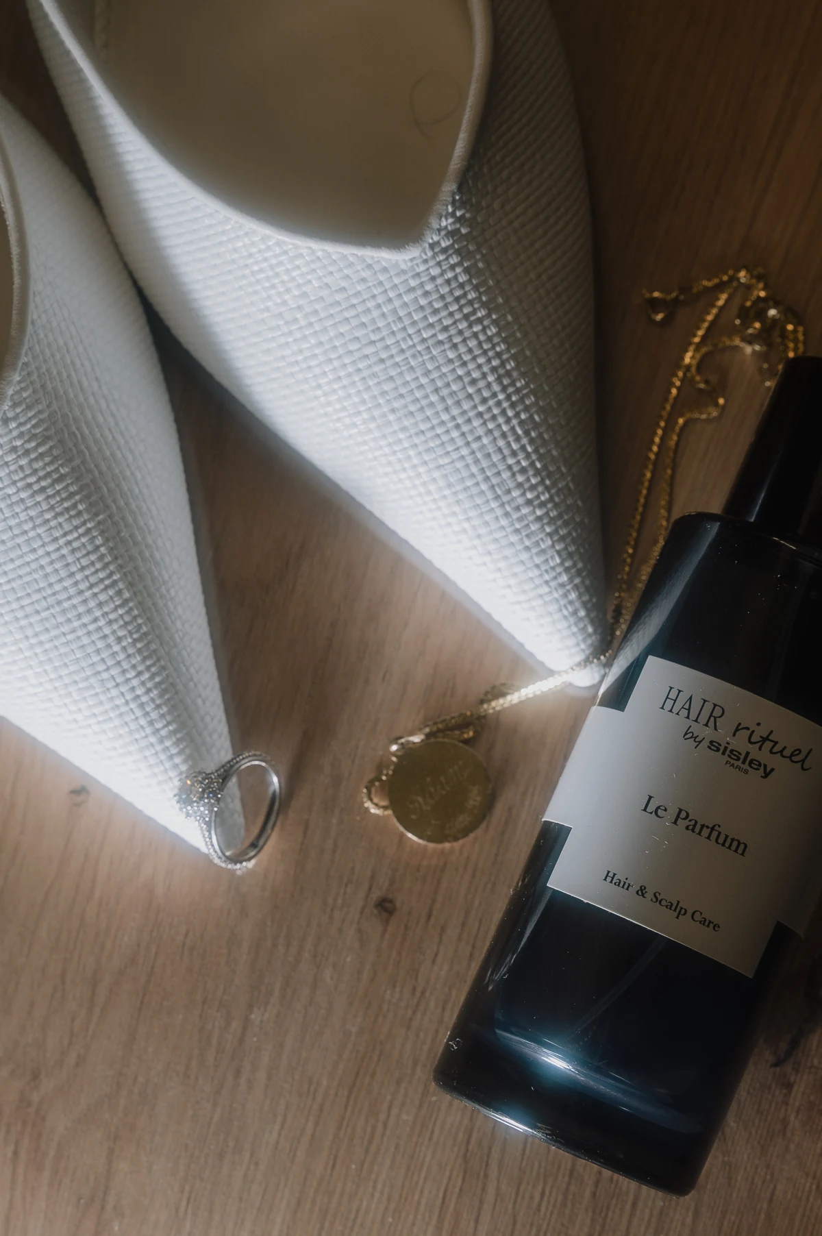 Mise à plat des accessoires de la mariée : chaussures, parfum, bague de fiançailles et collier de baptême
