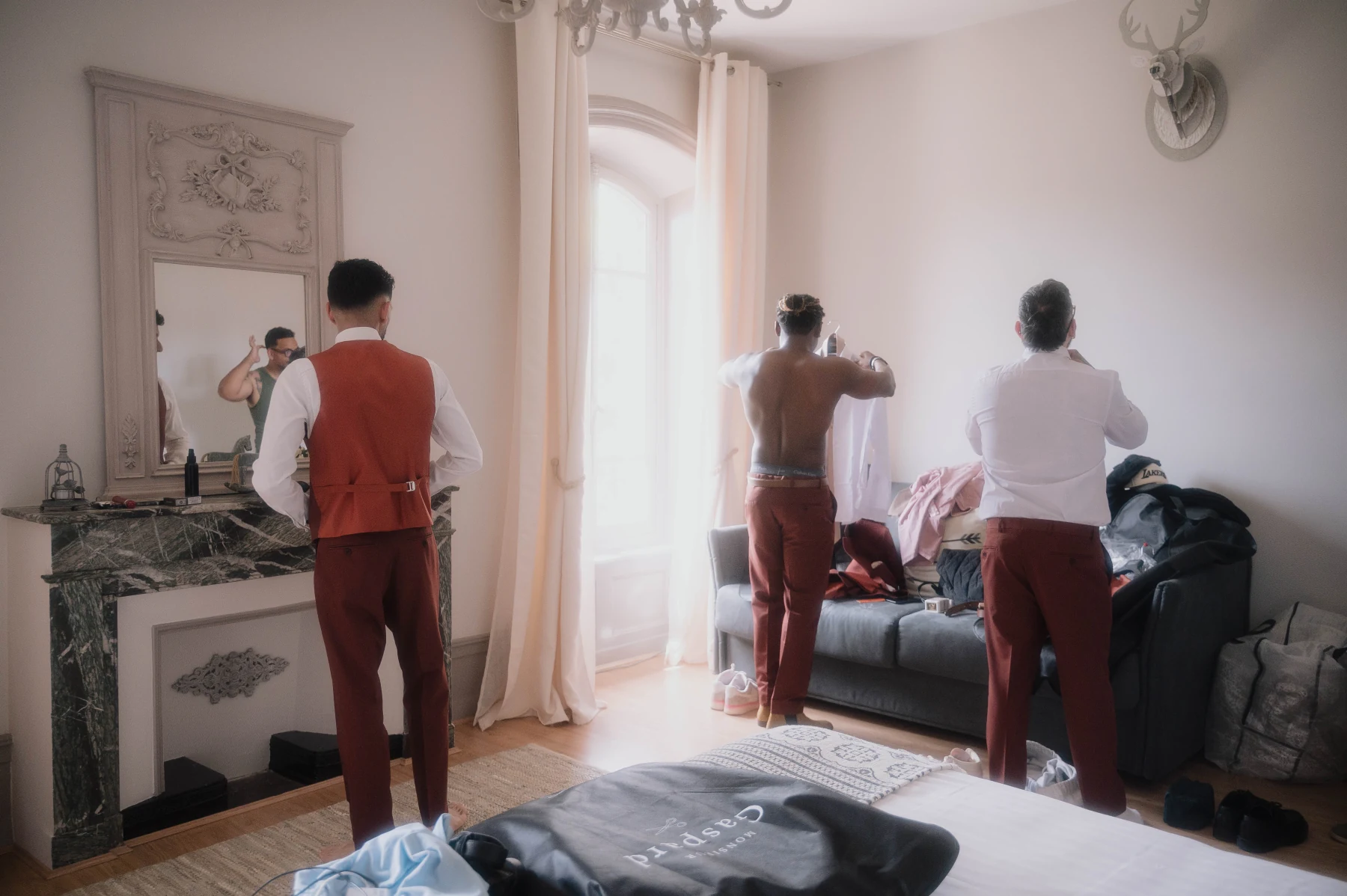 Les témoins du marié tournés vers le mur pendant qu'ils s'habillent, moment complice