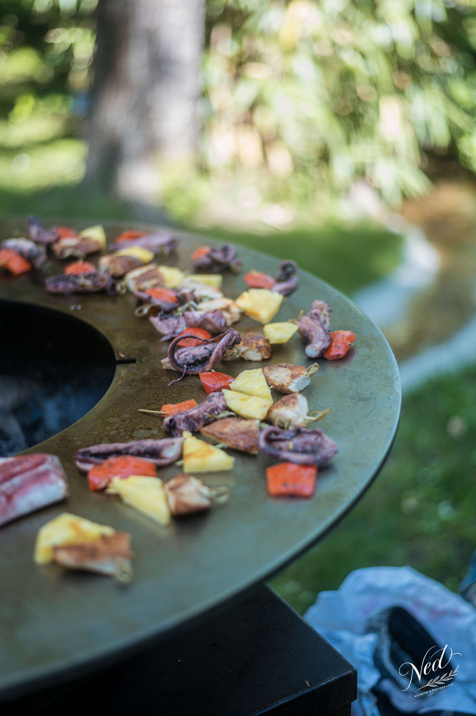 Brochettes de viande et légumes colorés disposées sur une assiette en ardoise dans un jardin ombragé