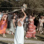 La mariée lève son bouquet pendant le jeu des rubans, les invitées en mouvement autour d'elle, Domaine de Bellevue