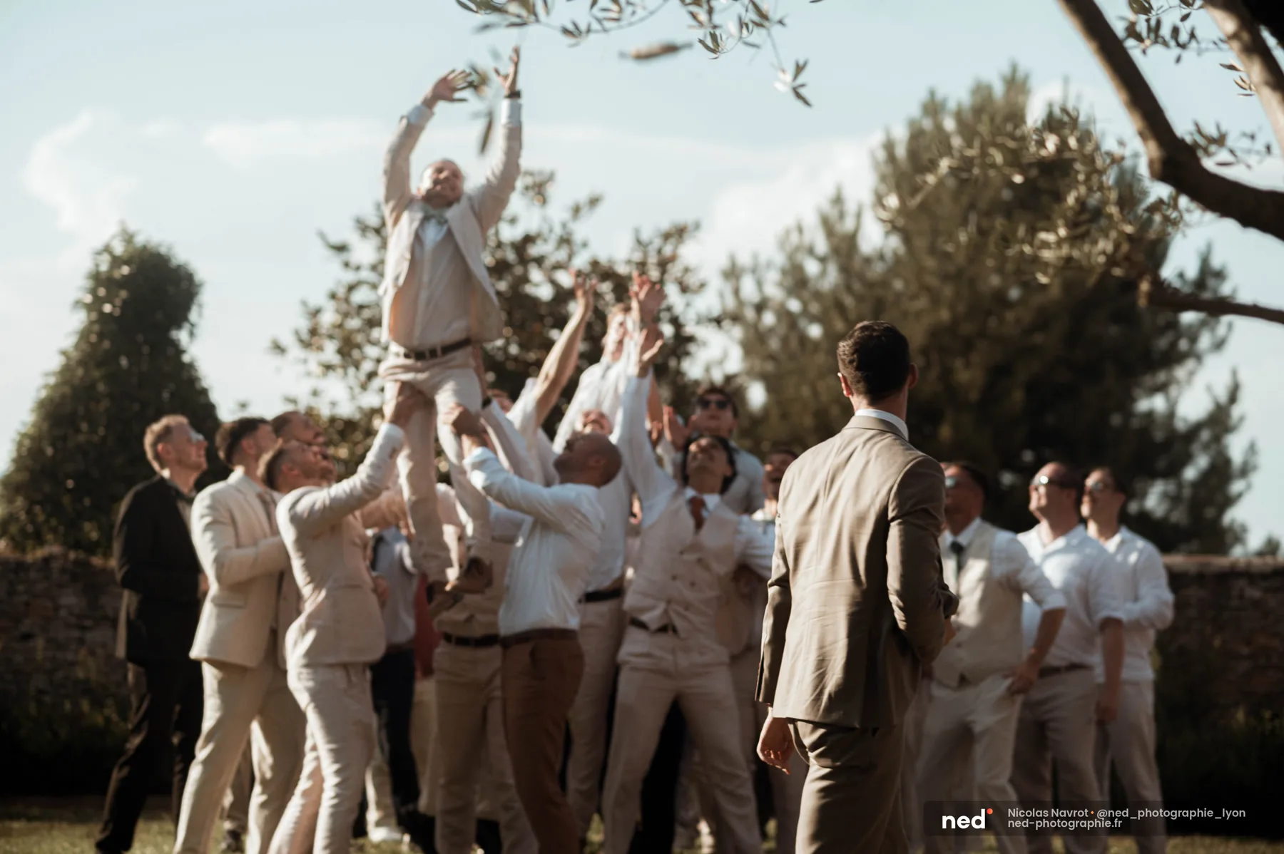 Un invité attrape le saucisson en plein vol porté par ses amis, moment de rire pendant la soirée de mariage dans le Beaujolais