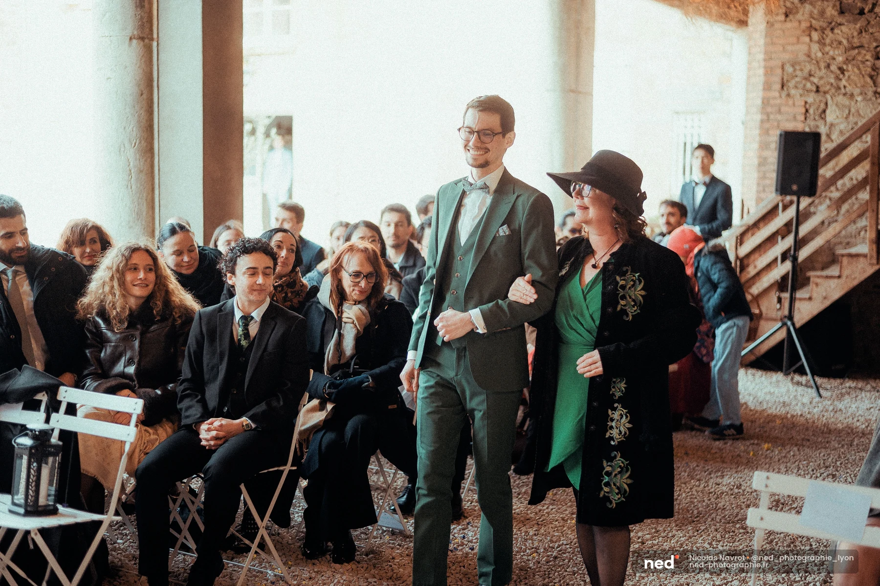 Marié costume vert sapin remonte l'allée cérémonie lieu en pierre, mariage au Domaine de Tourieux
