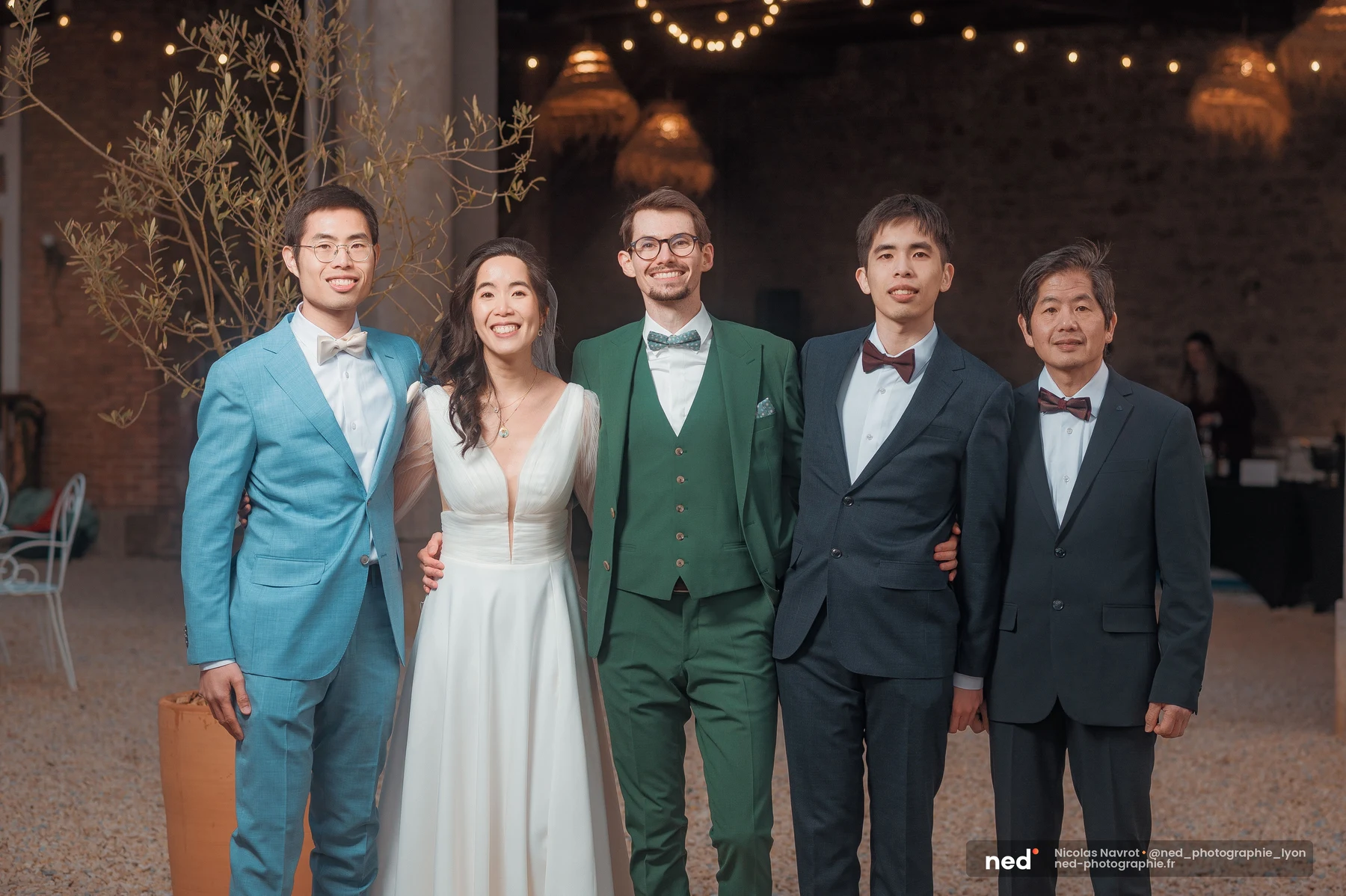 Mariés en robe blanche et costume vert entourés de quatre proches en salle, mariage au Domaine de Tourieux