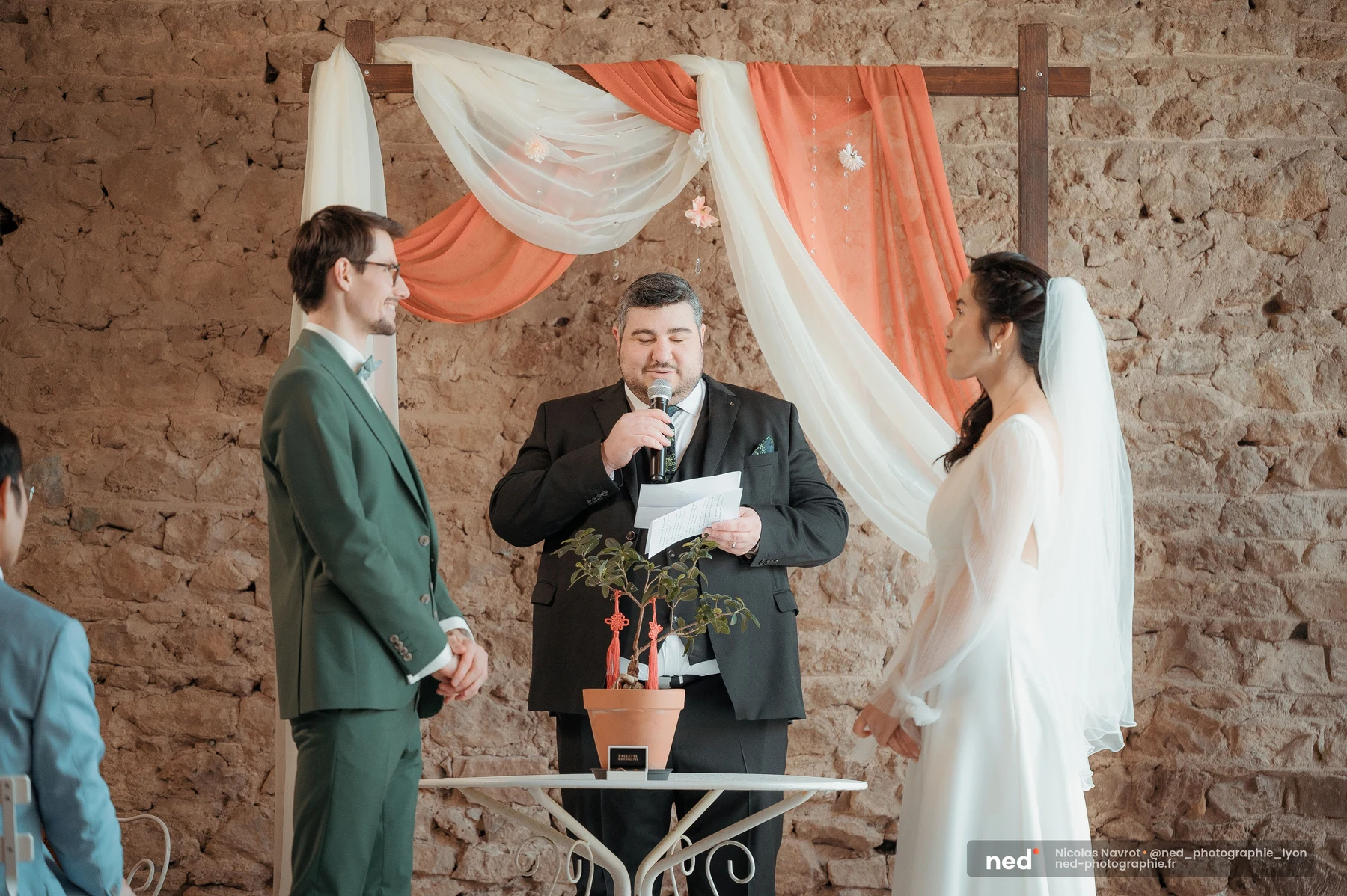 Cérémonie laïque mariés arche pierre officiant nœuds rouges arbre symbolique, mariage au Domaine de Tourieux