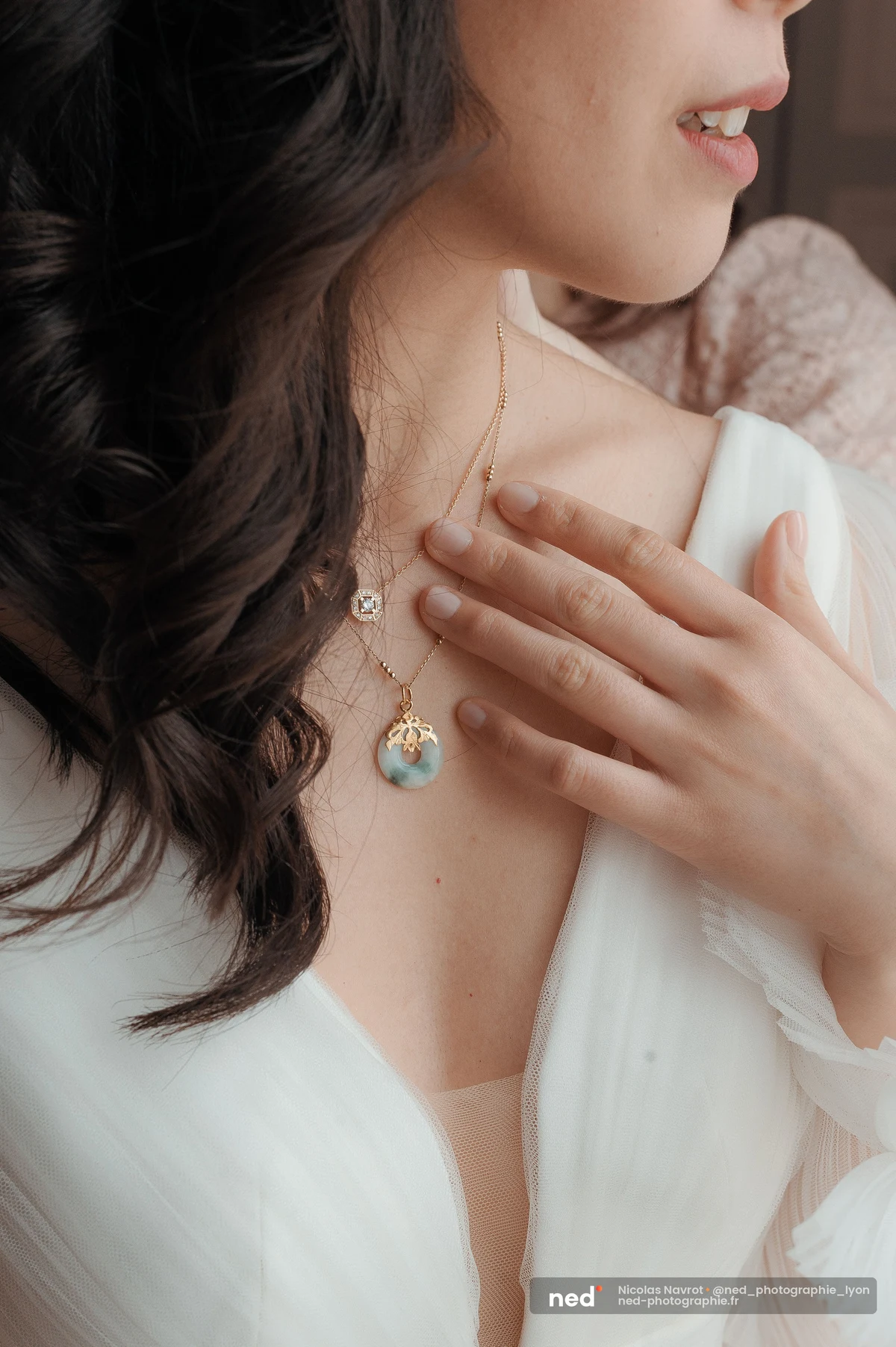 Colliers dorés superposés avec pendentif jade celadon portés par la mariée en robe blanche, mariage au Domaine de Tourie