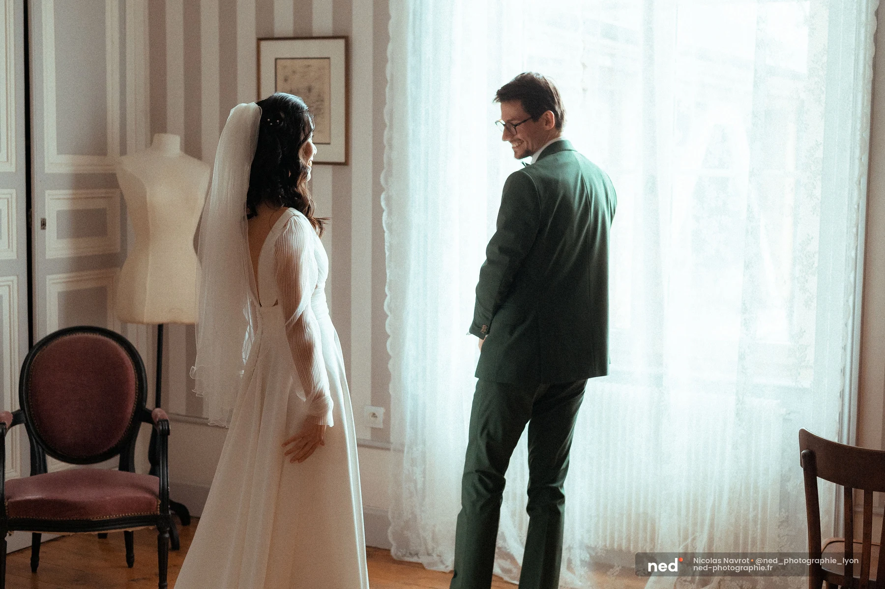 First look mariés robe blanche voile costume vert sapin intérieur fenêtre, mariage au Domaine de Tourieux
