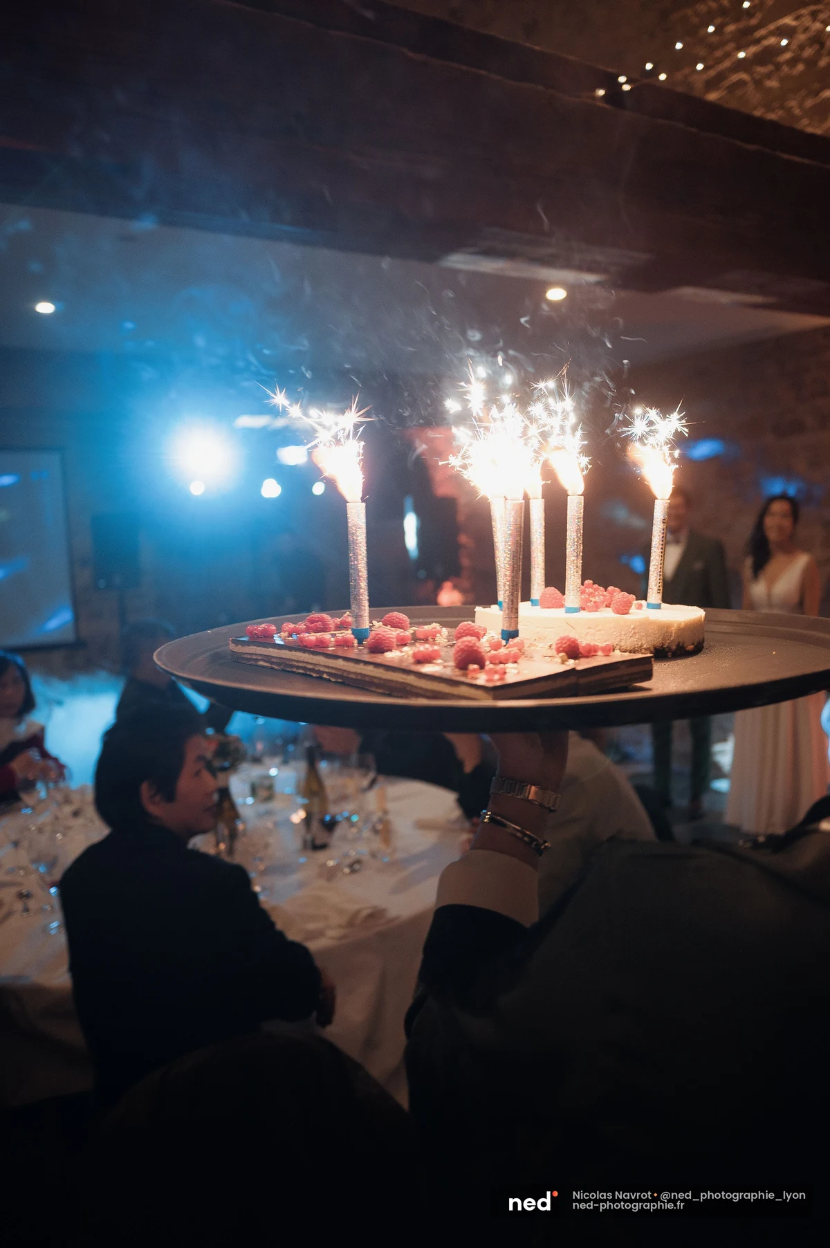 Gâteau mariage framboises porté sur plateau avec fontaines feu étincelles, mariage au Domaine de Tourieux