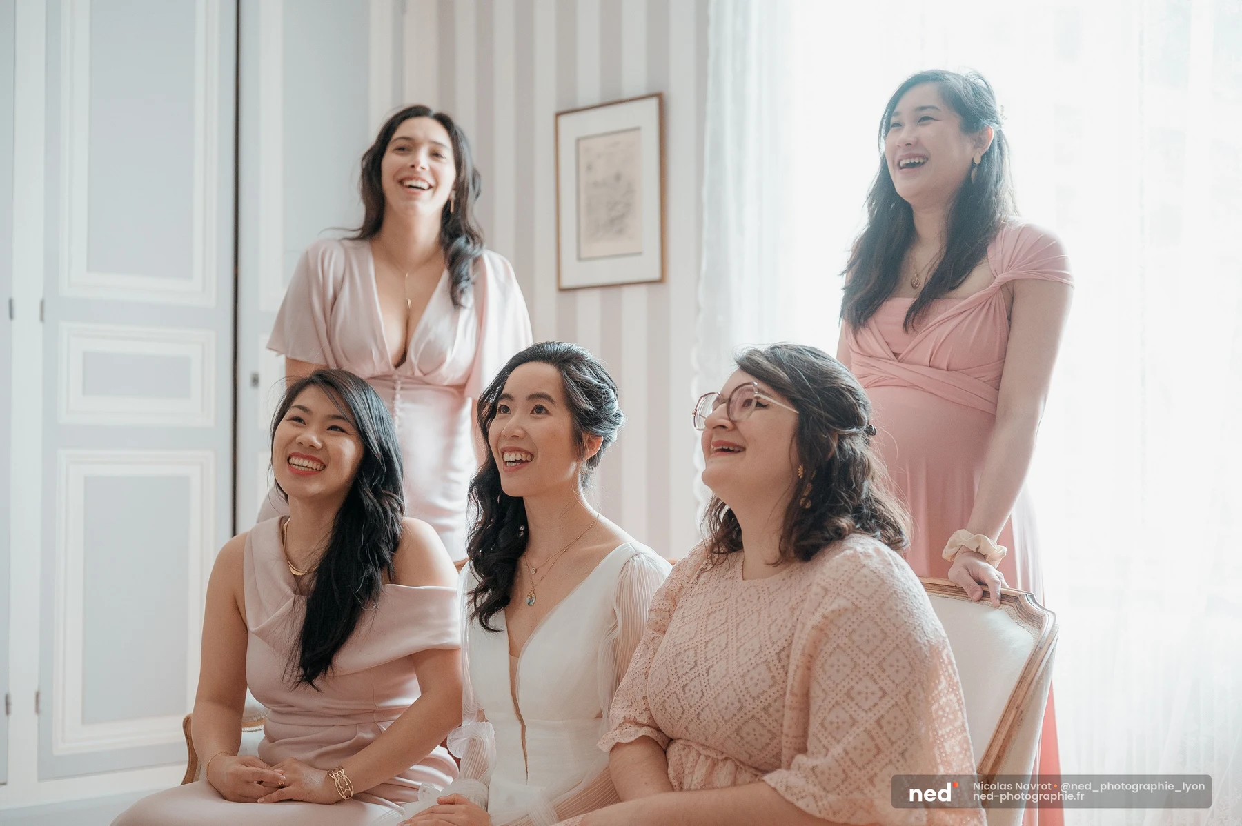 Mariée en robe blanche riant avec ses amies en robes roses lors des préparatifs, mariage au Domaine de Tourieux