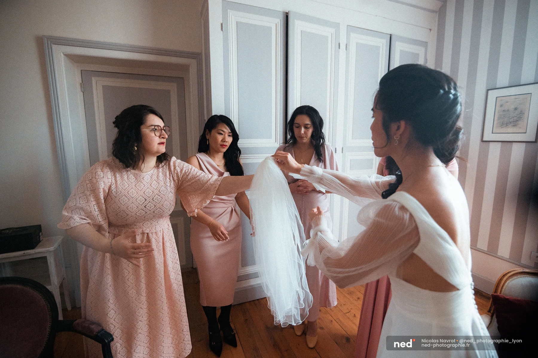 Mariée dos en robe blanche manches tulle déployant voile avec demoiselles honneur, mariage au Domaine de Tourieux