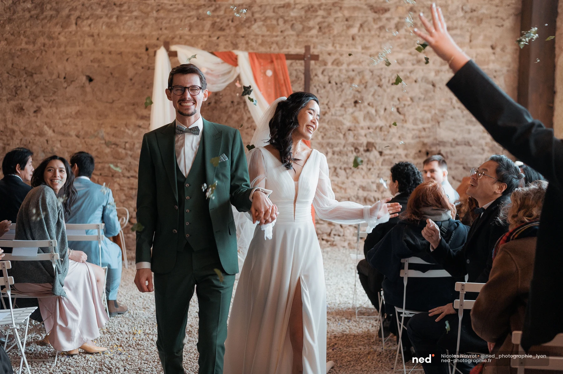 Mariés remontant l'allée sous une pluie de pétales lancés par les invités, mariage au Domaine de Tourieux