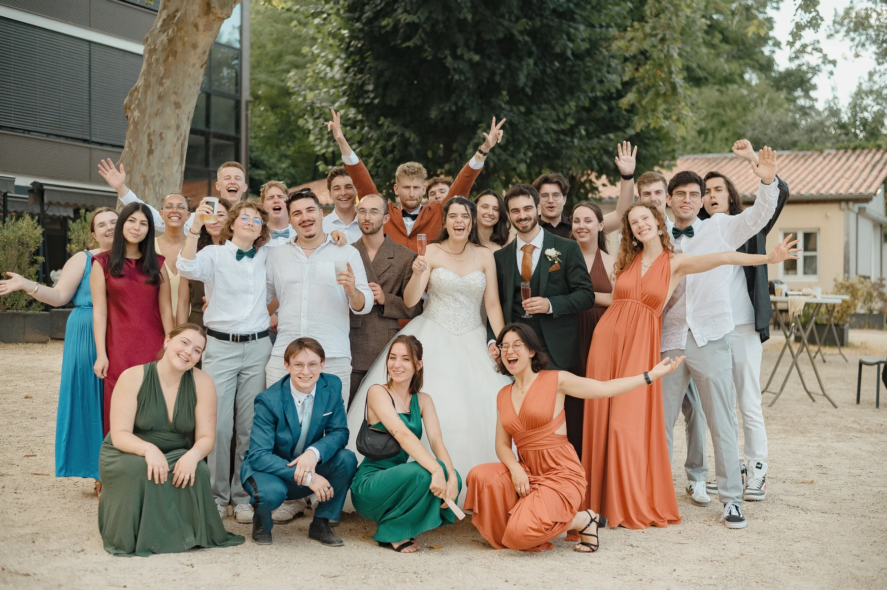 Photo de groupe animée mariés entourés d'amis en tenues colorées, extérieur, mariage au Oullins-Pierre-Bénite