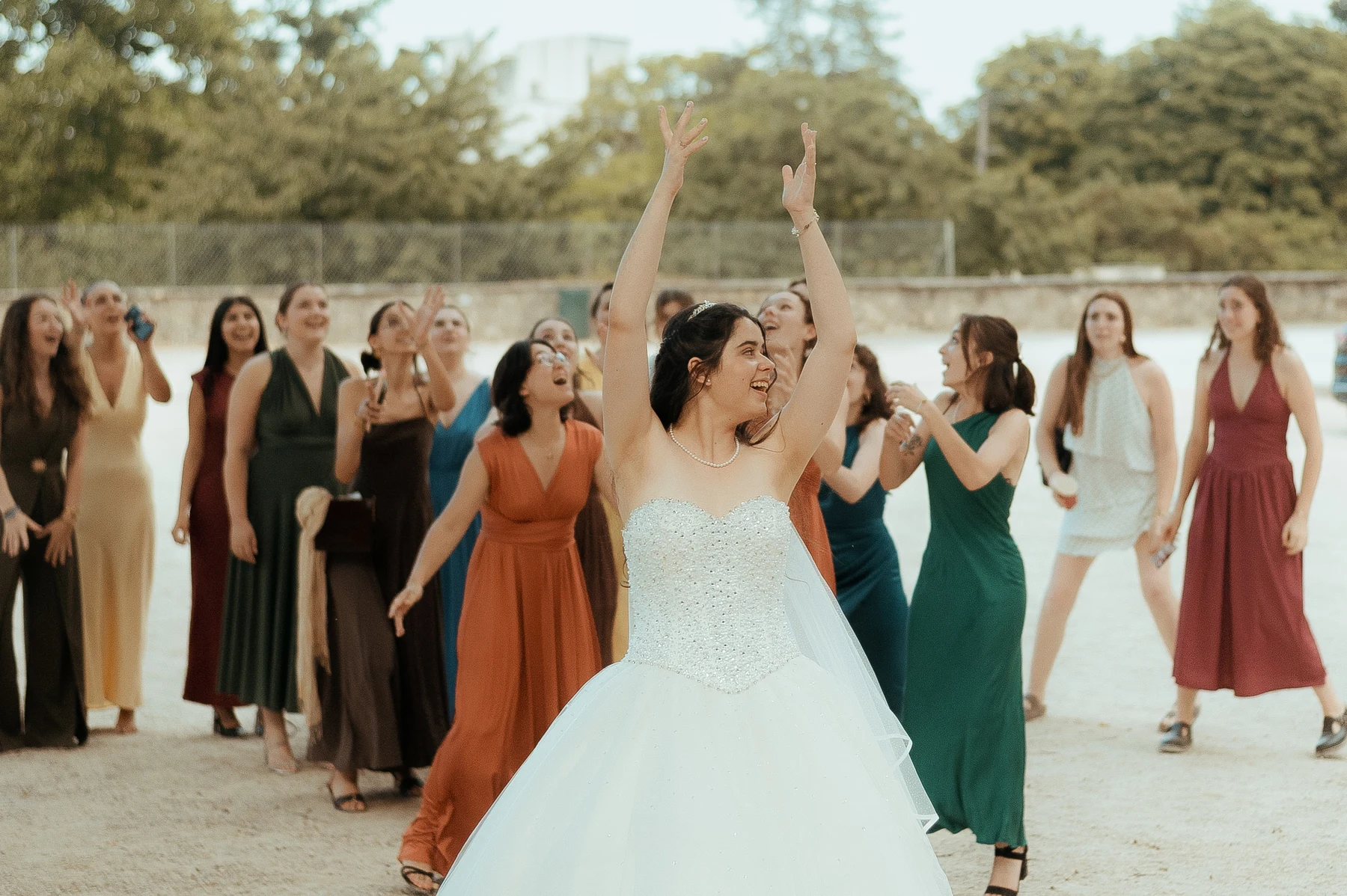 Mariée bras levés lançant le bouquet, invitées tendant les mains derrière, mariage au Oullins-Pierre-Bénite