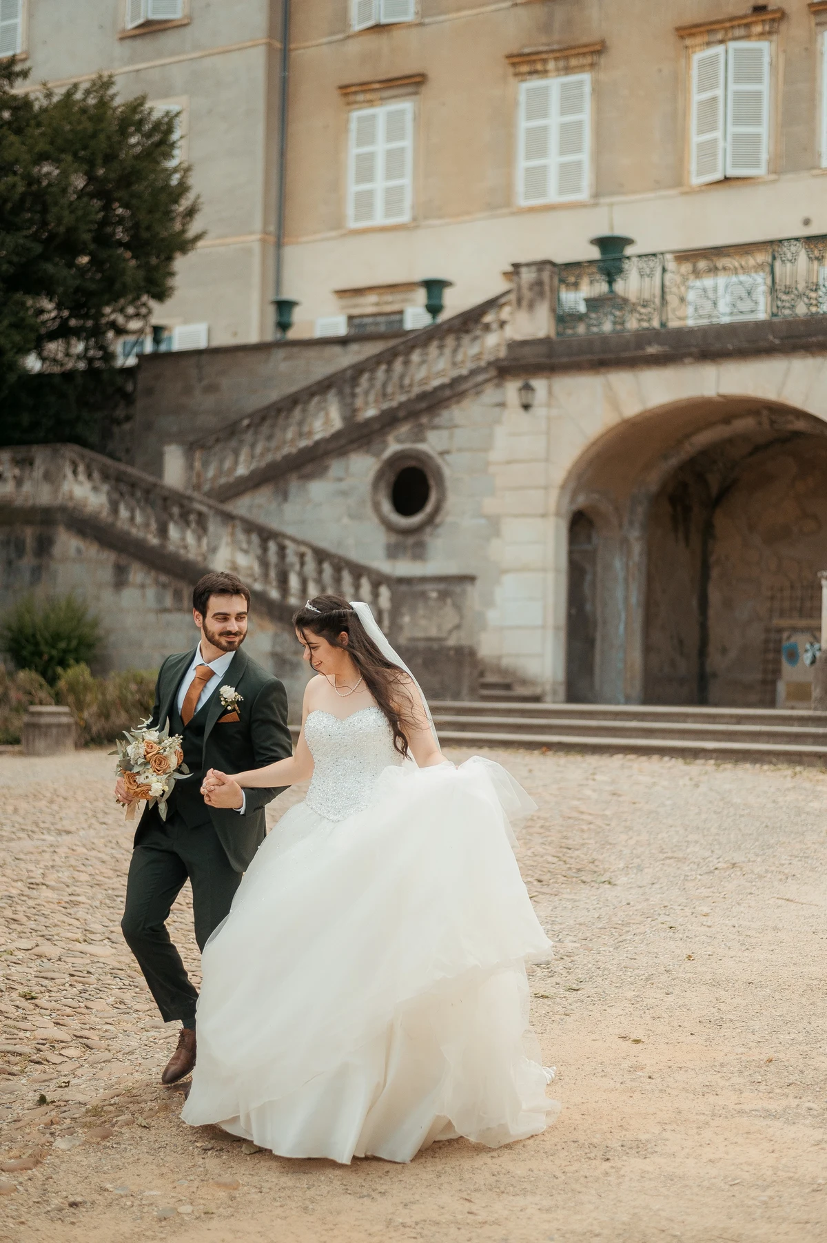 Mariés marchant devant château, robe de mariée tourbillonnant, mariage au Oullins-Pierre-Bénite