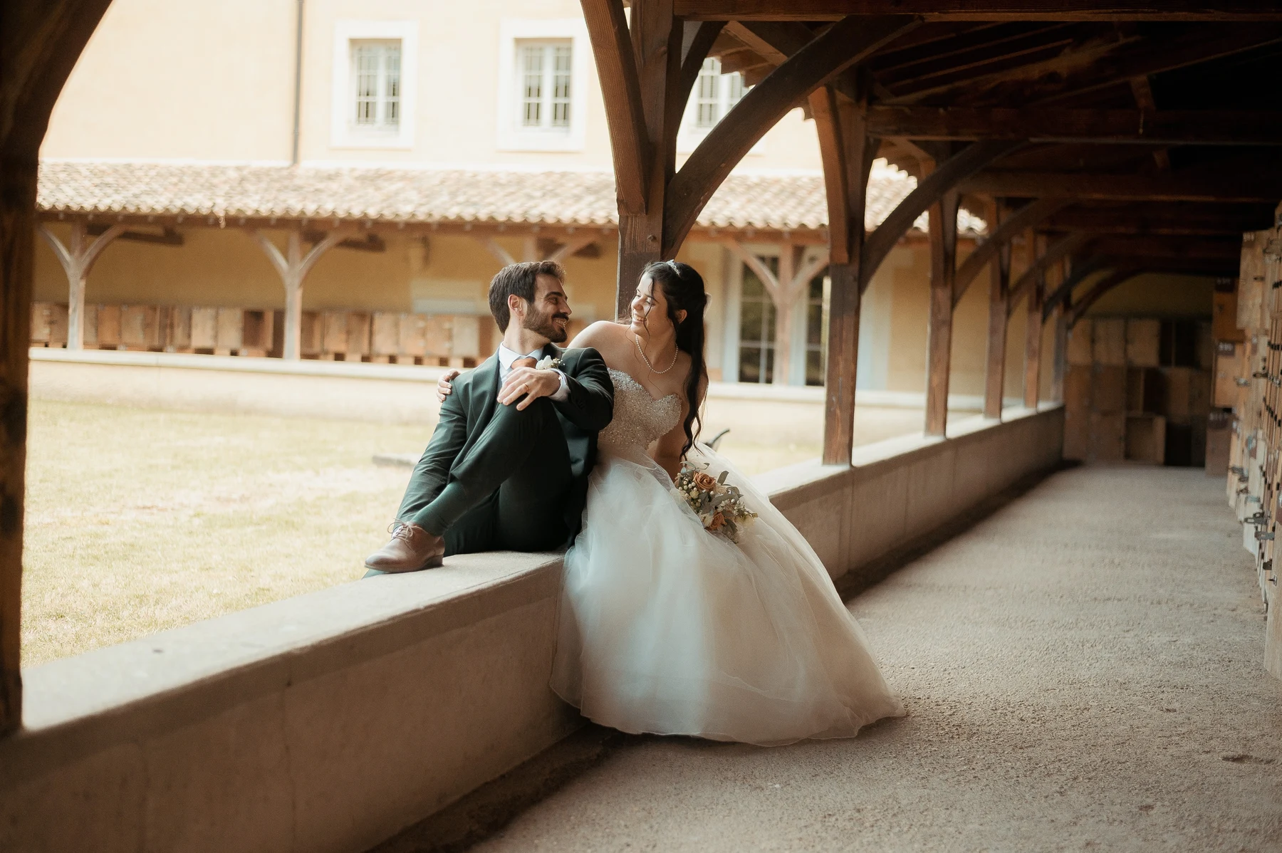 Mariés assis sous galerie en bois d'un domaine, robe blanche et costume vert, mariage au Oullins-Pierre-Bénite