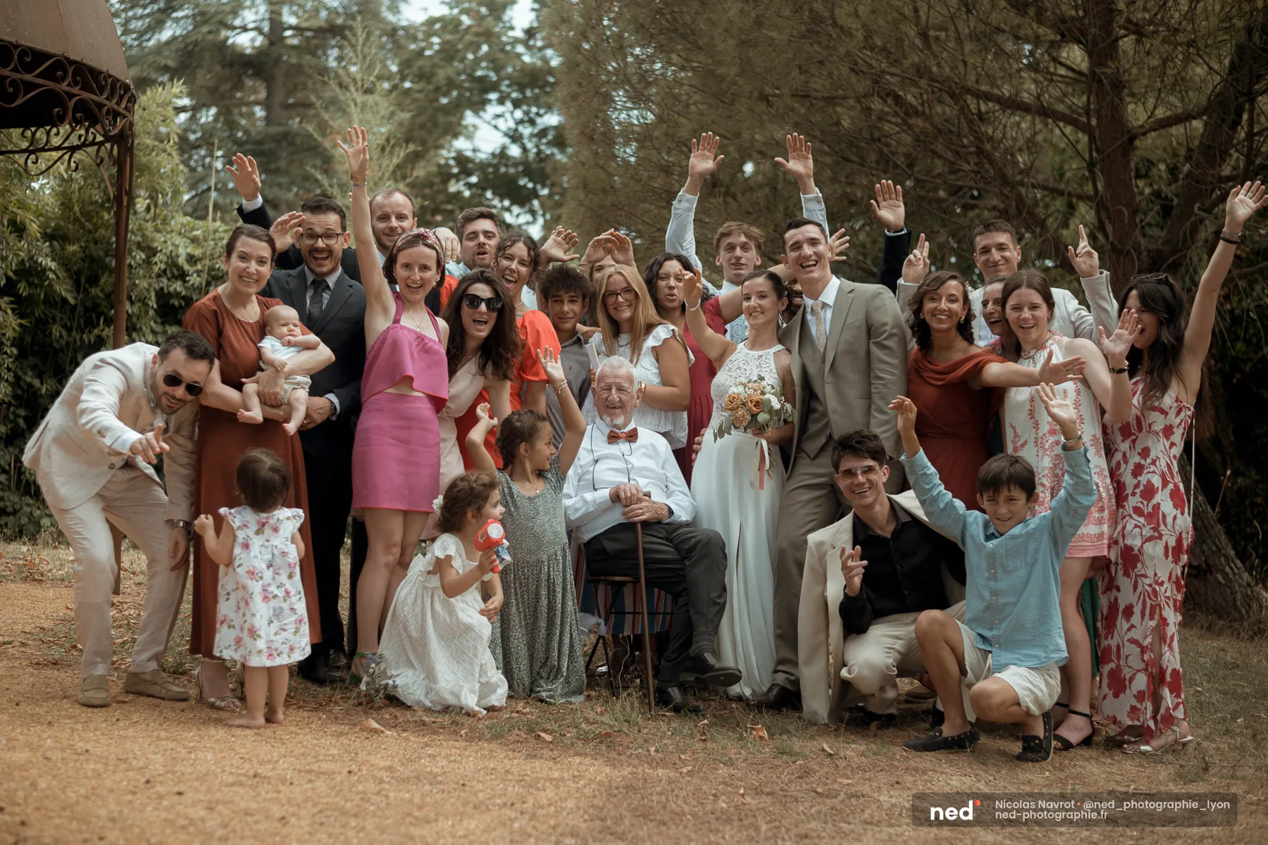 Photo de famille joyeuse près du kiosque du Domaine de Bellevue, le grand-père assis au centre entouré de tous