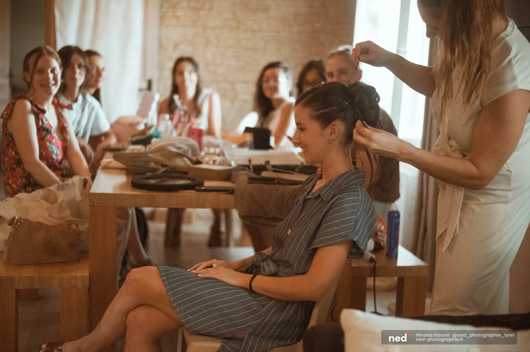 La mariée pendant sa coiffure, entourée de ses amies souriantes, préparatifs au Domaine de Bellevue à Anse
