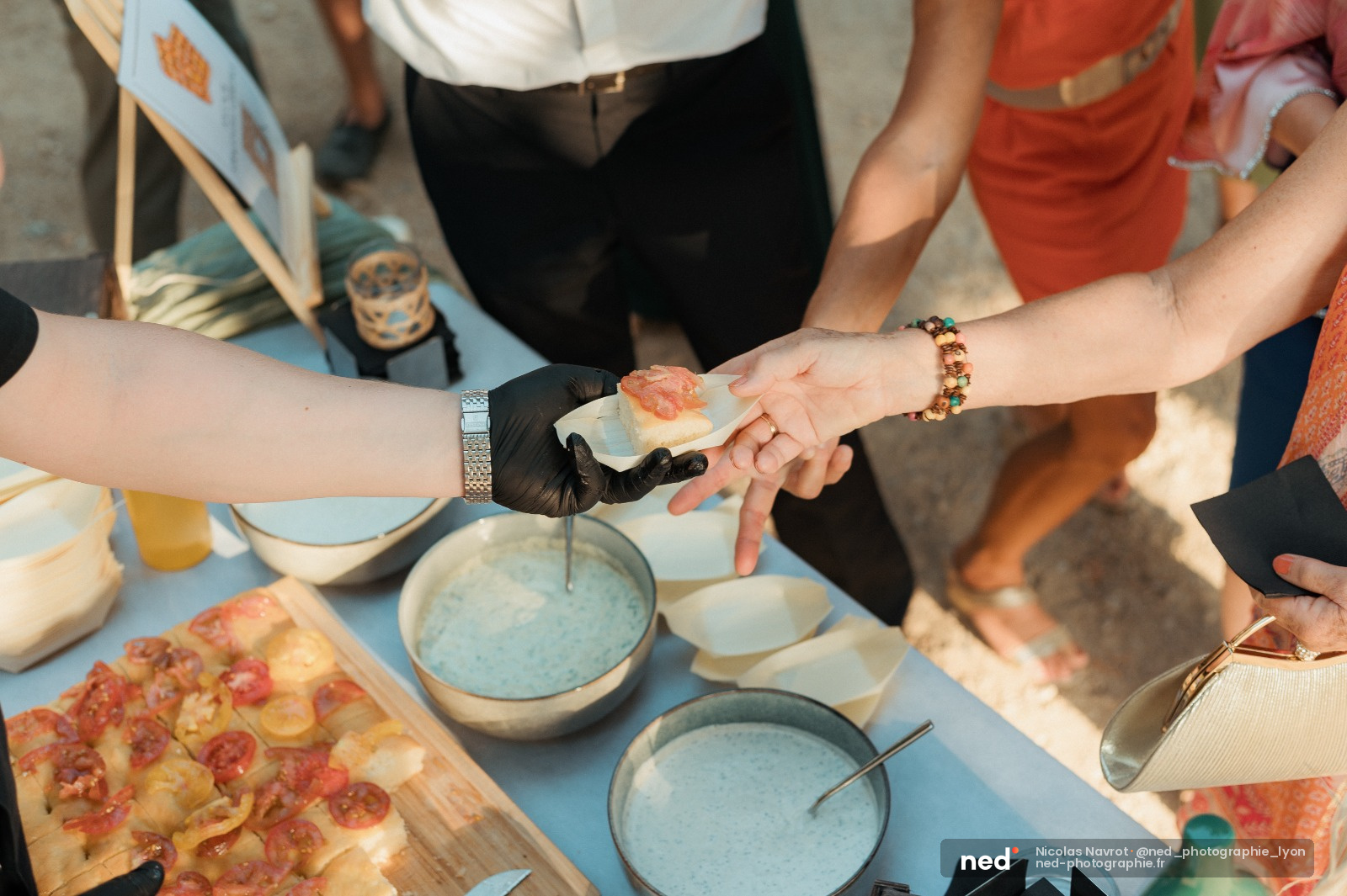 Groupe de participants en atelier culinaire trempent une tranche de pizza dans une sauce bleue, autour d'une table avec des bols.
