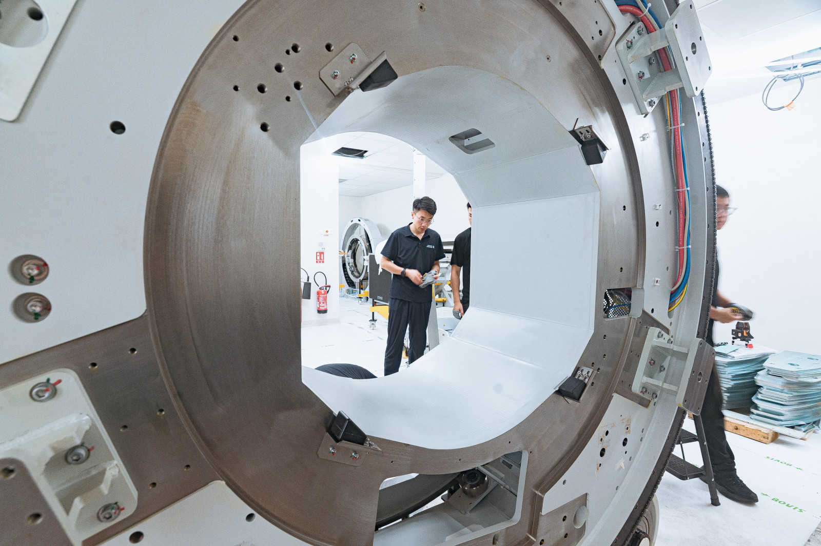 Vue à travers le tunnel de l'IRM avec un technicien au second plan