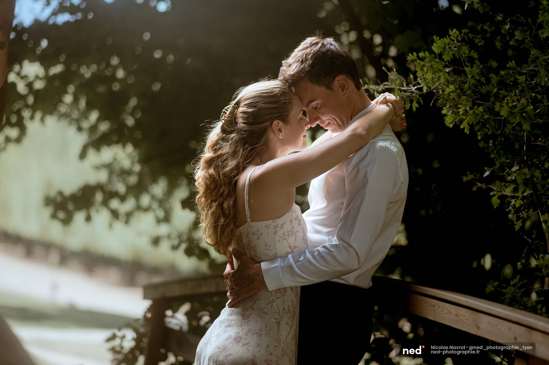 Couple enlacé front contre front dans une lumière dorée en sous-bois, séance photo de couple au Château du Sou