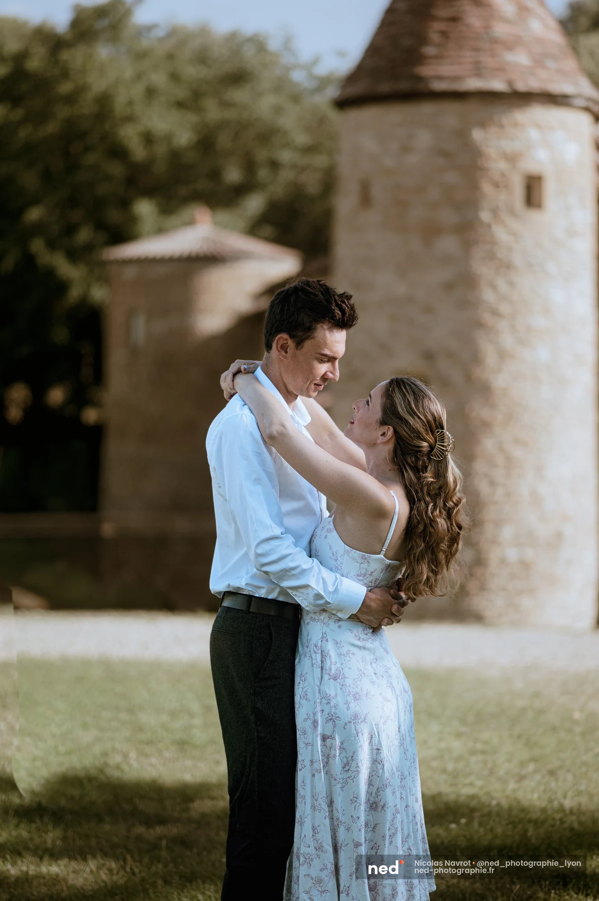Couple enlacé face à face devant une tour de château en pierre, séance photo de couple au Château du Sou