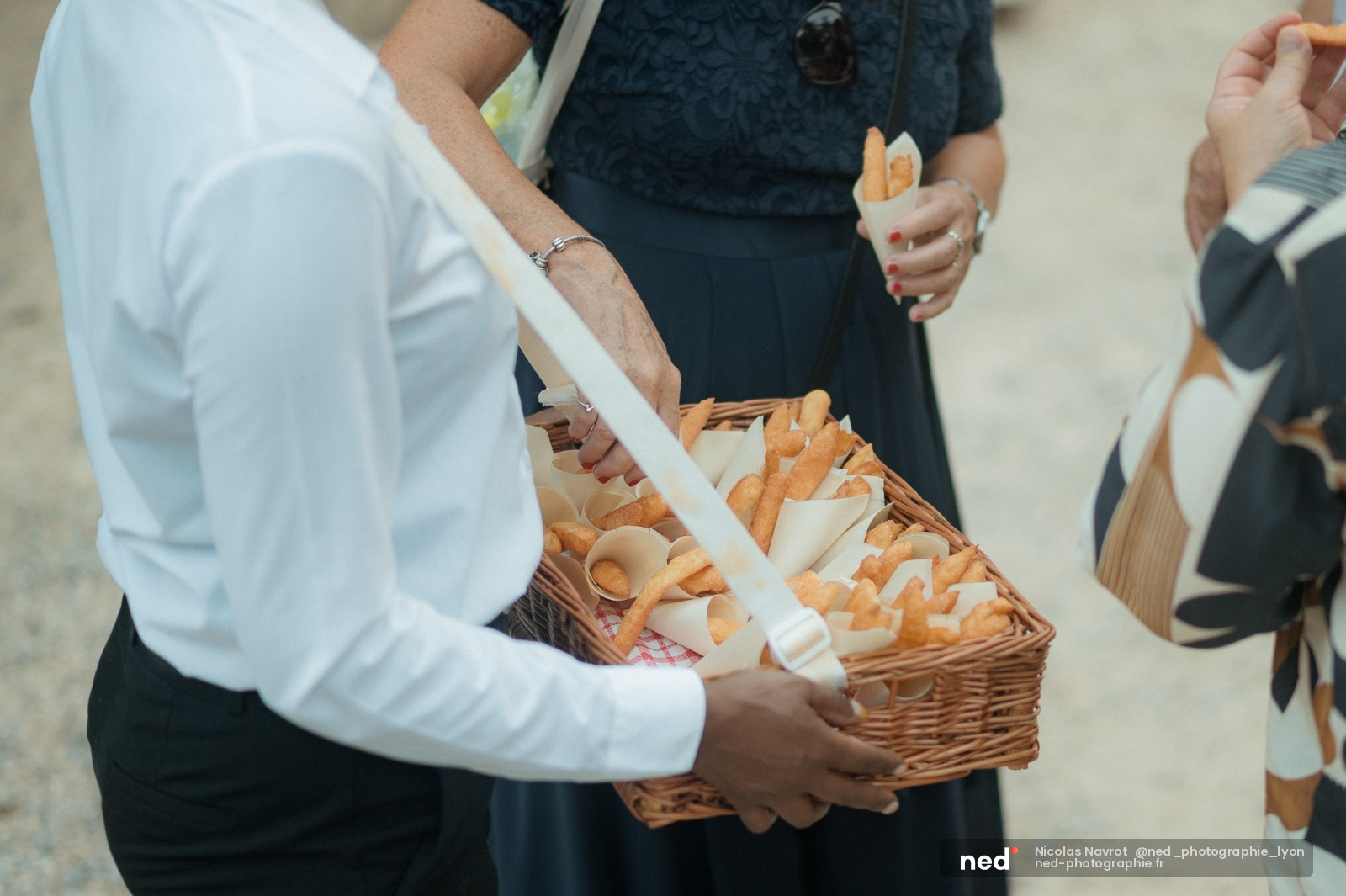 Homme en chemise blanche tenant un panier en osier rempli de pain et viennoiseries à un mariage