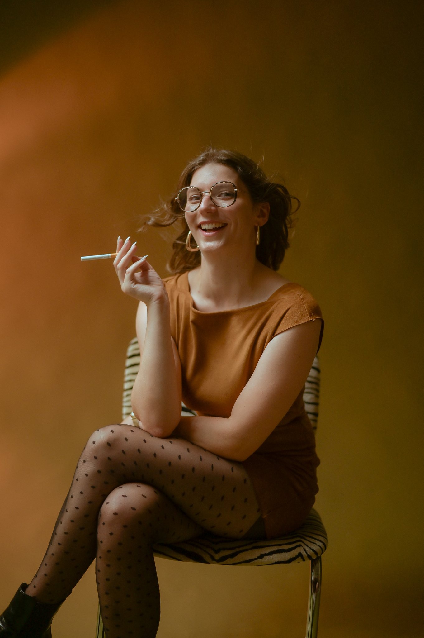 Portrait en studio à Lyon, ambiance années 70, femme assise sur fond orange, lumière chaude