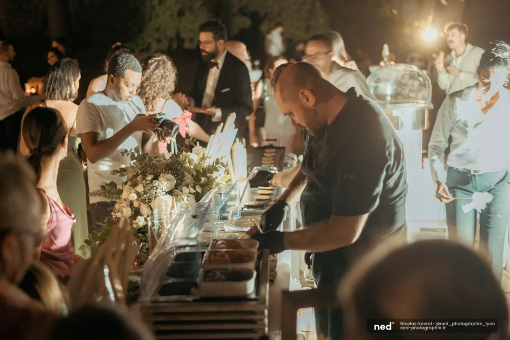 Cuisinier en gants noirs servant des plats sous lumière dure lors d'un buffet nocturne, photographe culinaire Lyon