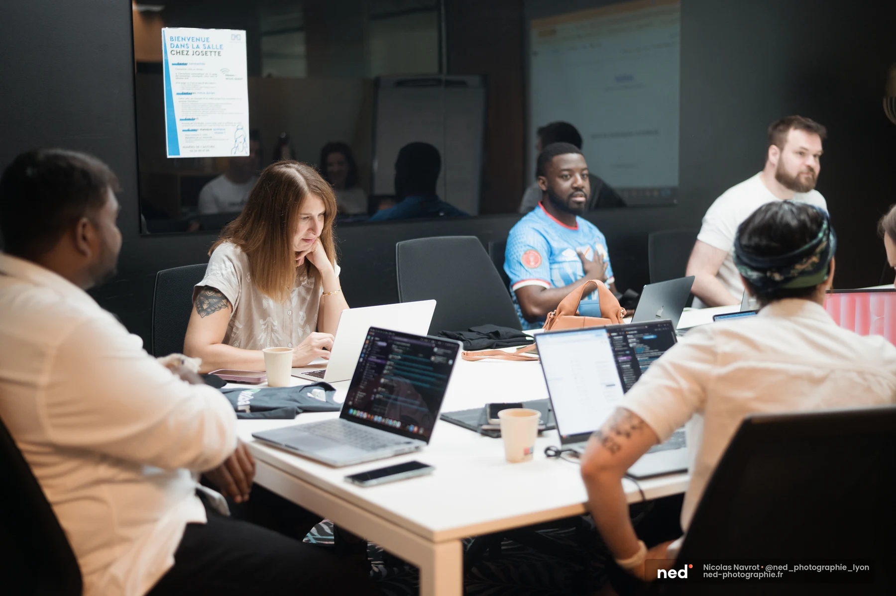 Équipe réunie dans une salle nommée « Chez Josette », chacun devant un laptop ouvert, en pleine session de travail collectif.