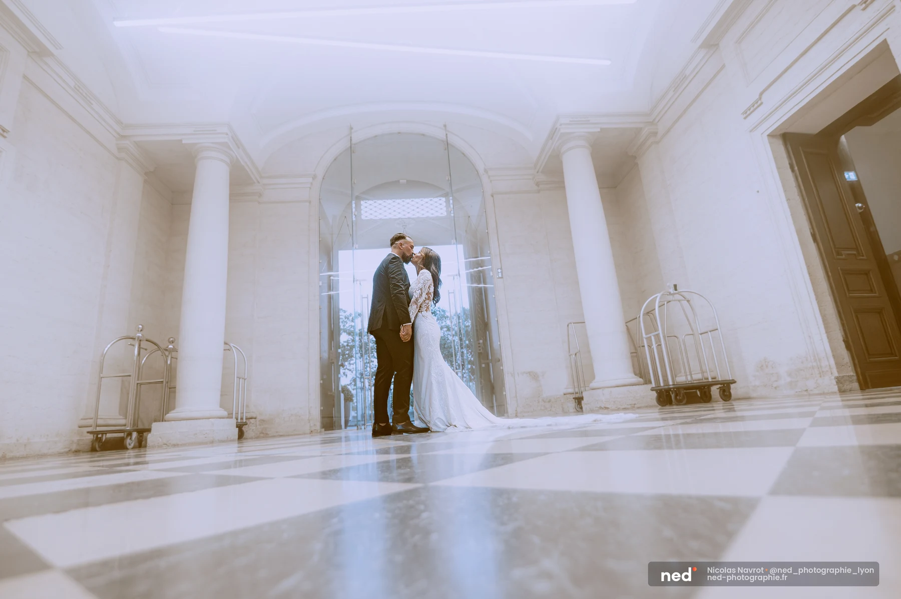 Couple de mariés s'embrassant dans hall monumental carrelage losanges clairs, séance photo couple à Pl. de l'Hôpital