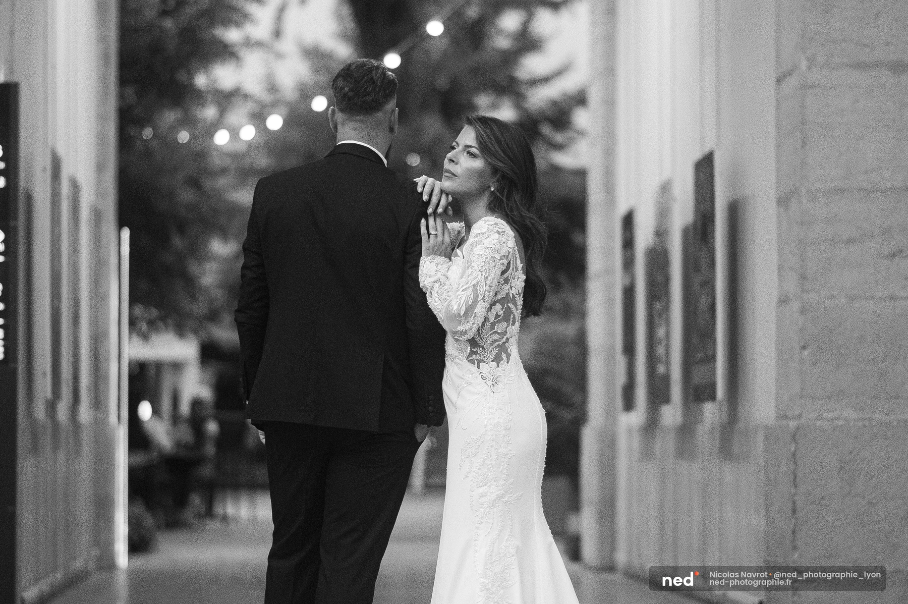 Mariée en robe dentelle posant la main sur l'épaule du marié, noir et blanc, séance photo couple à Pl. de l'Hôpital
