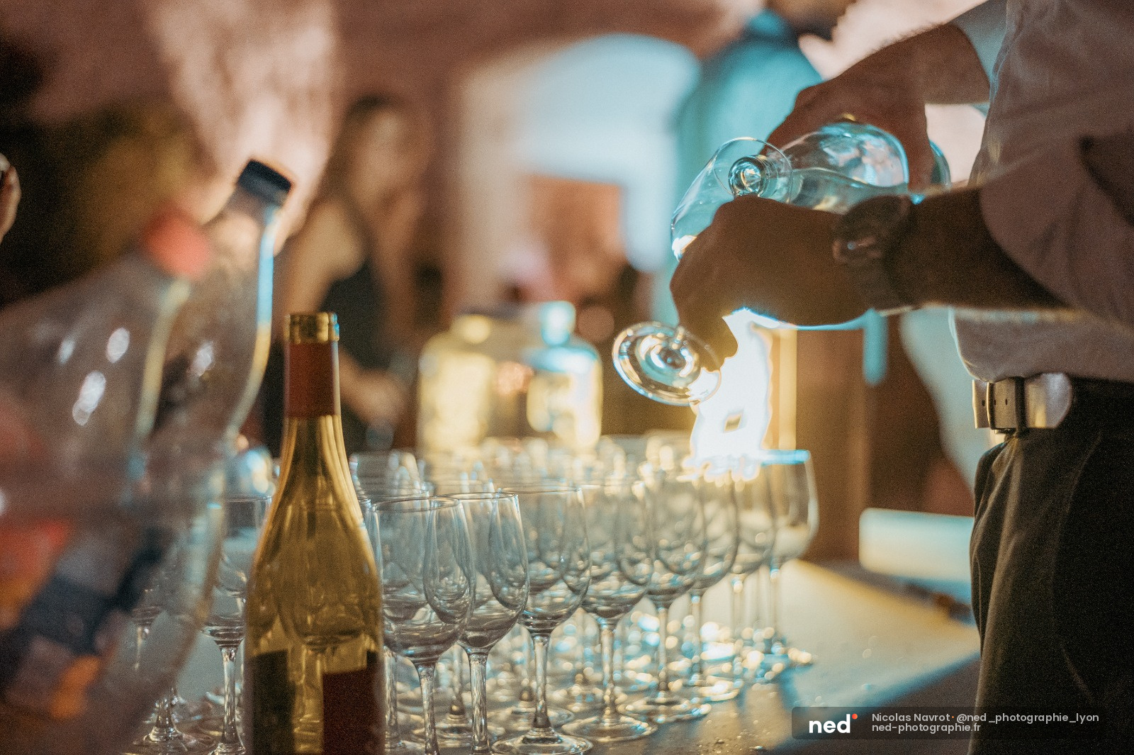 Serveur versant du champagne dans des coupes en cristal lors d'une réception, verres alignés sur table
